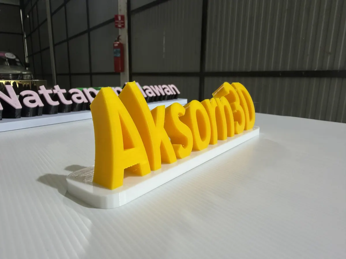 ป้าย Aksorn3D สีเหลืองบนฐานขาวด้านหน้า ใช้ฟังก์ชั่น 3D mini ทำป้ายแบรนด์ตั้งโต๊ะ