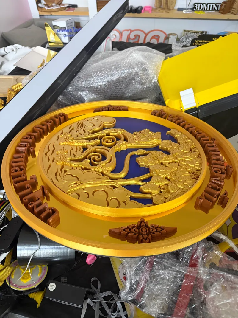 Gold circular emblem with raised Thai lettering and ornamental details