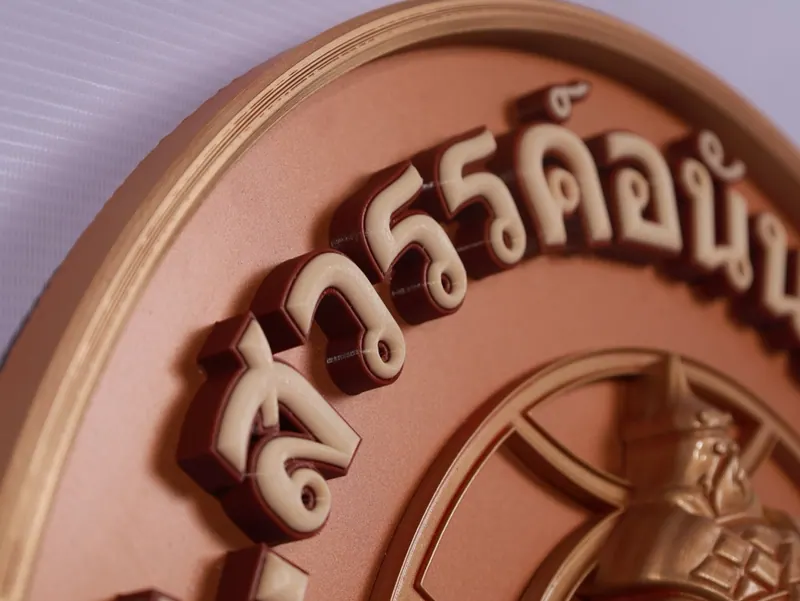 Raised Thai typography on a circular logo panel