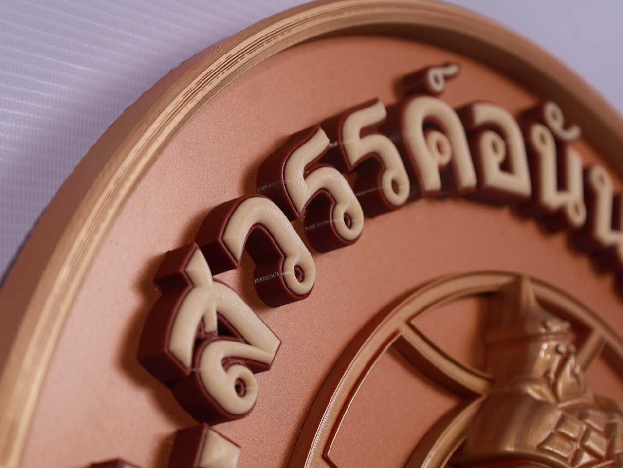 Raised Thai typography on a circular logo panel
